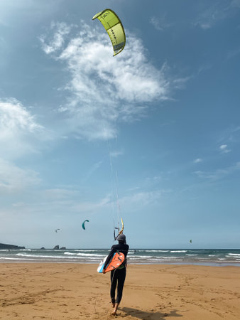 A vertical shot of a rear view of a person kitesurfing in Liencres, Cantabria, Spainの写真素材