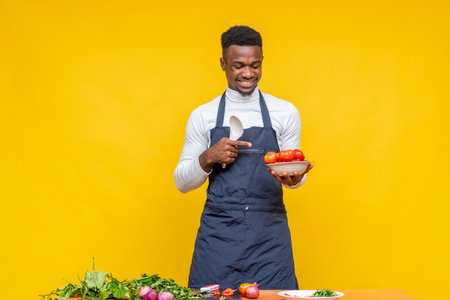 A closeup shot of an African male chef preparing food in front of a yellow wallの写真素材