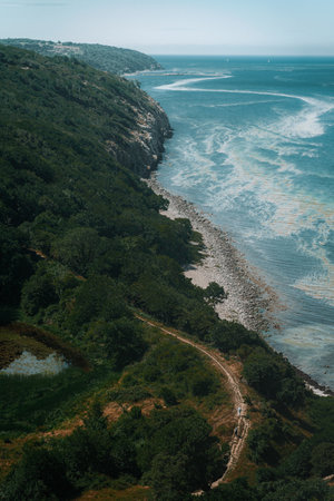 An aerial view of mountain forests and calm blue sea under a clear skyの写真素材