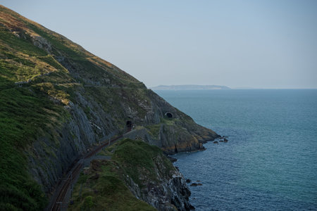 Scenic seascape of the Irish coast with characteristic train tunnels crossing the Bray Head mountain in County Wicklow, Ireland.の写真素材