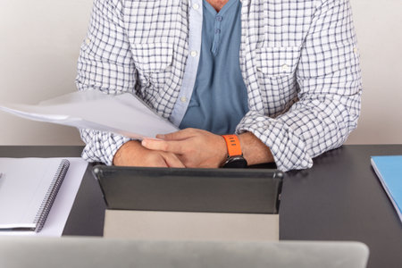 A Caucasian man with a tablet and a folder in his hand on his work table at homeの写真素材