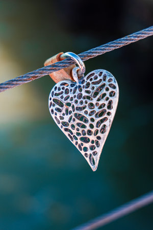 A shallow focus shot of a silver heart and lock on a metal wireの写真素材