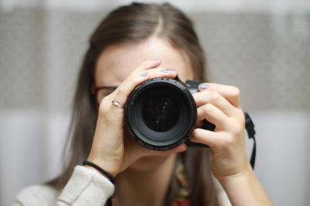 A closeup shot of a female using a professional cameraの写真素材