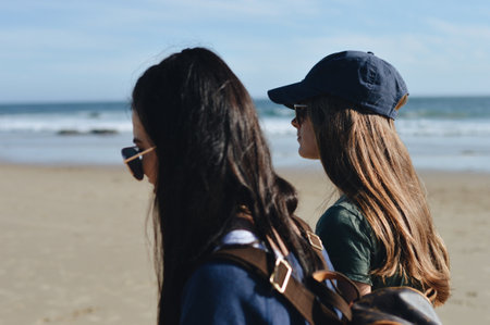 A pair of young female friends walking on a beachの写真素材