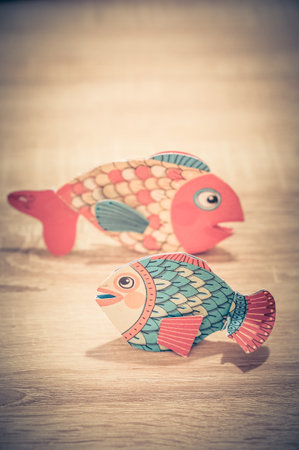 A vertical shot of paper fishes on a wooden table