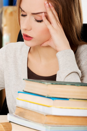 A young Caucasian woman from Poland having a headache with books in frontの写真素材
