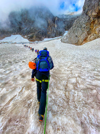 Hiking group in a chain to the top of the peak in Germany
