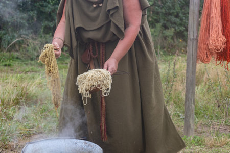 A shot of a woman in historic clothes in a prehistoric museum washing wool like in the pastの写真素材
