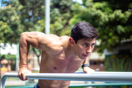 A determined young Hispanic guy working out intensely in a sunny park