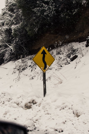 A yellow sign in snow on the roadの写真素材