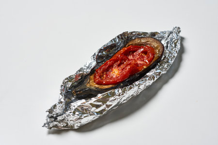 A delicious dish made of eggplant with tomatoes on a foilの写真素材