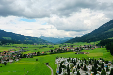 A landscape of a town surrounded by hills covered in greenery in Brixen im Thale, Austriaの写真素材