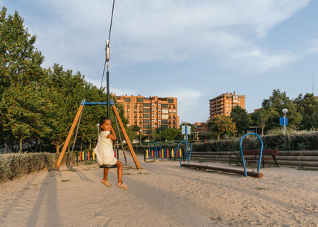 A closeup shot of a Hispanic cute little girl on the swing in the playground in Spainの写真素材