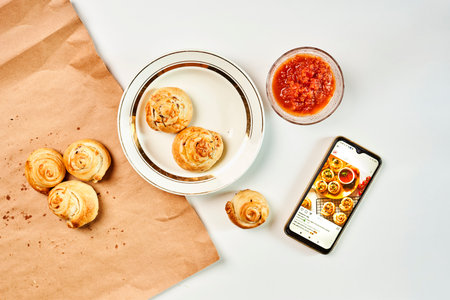 A fresh bakes with sauce next to the phone on the table