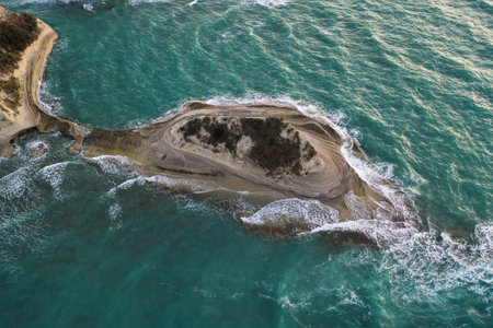 A drone view of a half-island surrounded by the sea on a sunny day