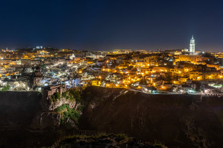 An aerial night cityscape of Matera city on a rocky outcrop in  Basilicata, in southern Italy