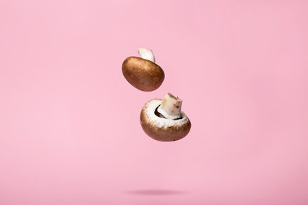 A closeup of fresh Agaricus bisporus falling against a pink backgroundの写真素材