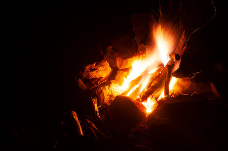 A campfire burning in the nighttime at a campsite.