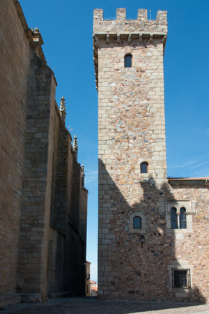 A vertical shot of the Torre De Las Ciguenas under the sunlight and a blue sky in Caceres, Spainの写真素材