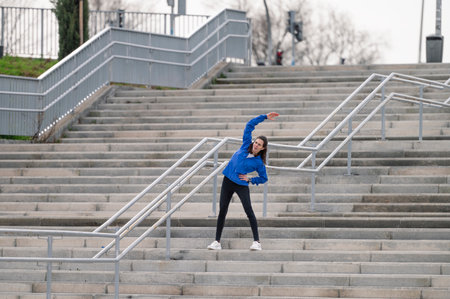 A young Caucasian female jogger doing physical exercises and stretching on a staircase