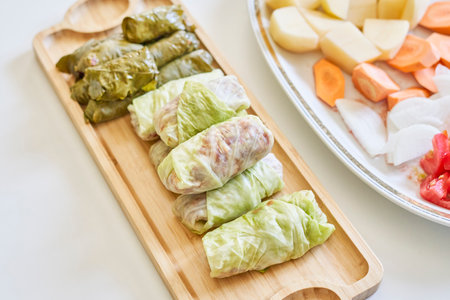 The stuffed cabbage and grape leaf rolls on a wooden plate in the kitchenの写真素材