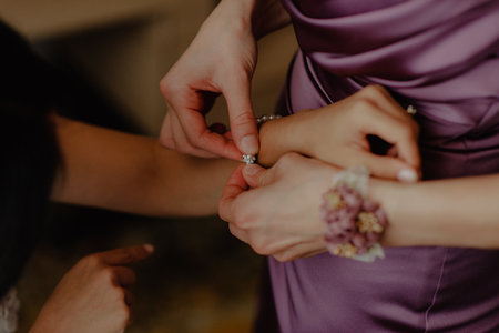 A closeup shot of a bridesmaid putting on the bride's braceletの写真素材