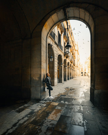 An Italian cool man leaning on the entrance arch of an old buildingの写真素材