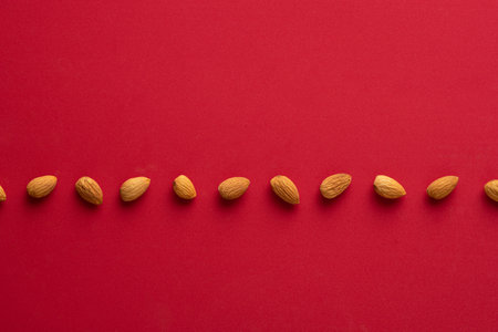 A top view of almonds on a red surface under the lightsの写真素材