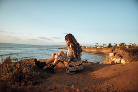 A rear view of a female sitting on the beach watching the beautiful seascapeの写真素材