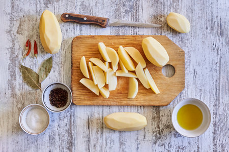 A top view of sliced potatoes with seasonings on a wooden surfaceの写真素材