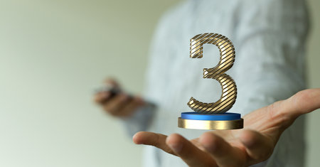 A 3d rendered golden 3 on a pedestal hovering over a man's palm - award and anniversary conceptの写真素材