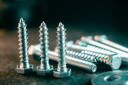 A closeup of the metal silver screws against the dark backgroundの写真素材