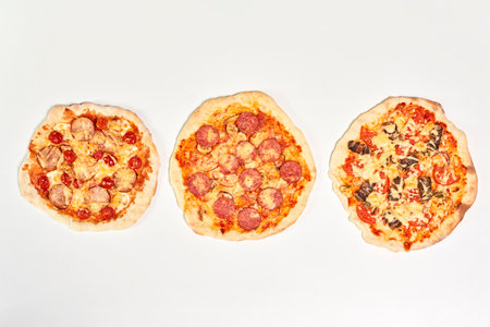 A top view of three types of pizza on a white surfaceの写真素材