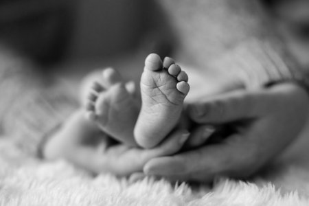 A selective focus shot of the feet of a baby in mother's handsの写真素材