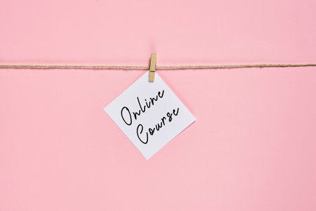 A card with online course lettering on a rope with a pin isolated on pinkの写真素材