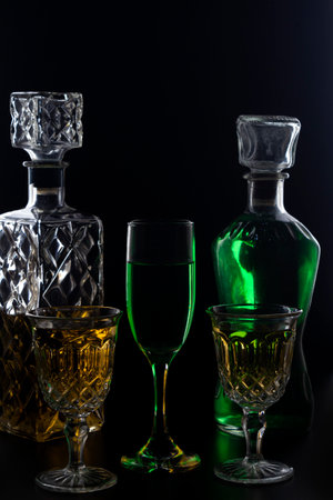 The wine glasses and bottles with liquids on a dark background