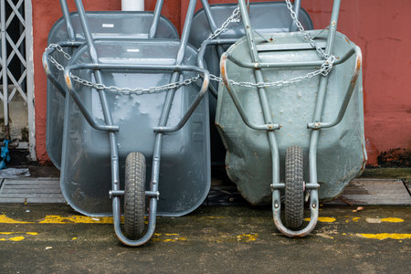 A shot of chained gray garden wheelbarrows against a red wallの写真素材