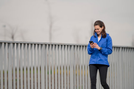 A young female walking and smiling while looking at her phone screenの写真素材