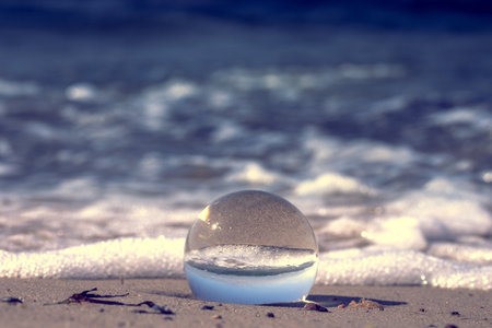A crystal ball with the reflection on the sandy beachの写真素材