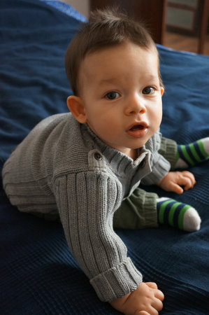 A portrait of a Polish baby boy sitting on the bed and looking at the camera, face with mouth openの写真素材