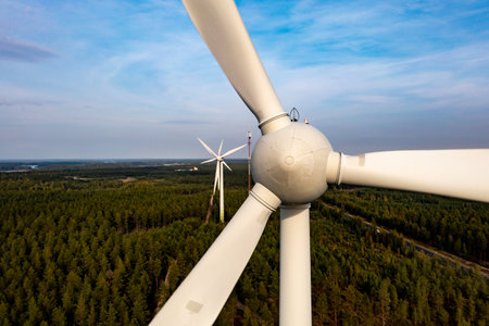 Aerial drone view in front of a windmill or a wind power turbines, golden hour