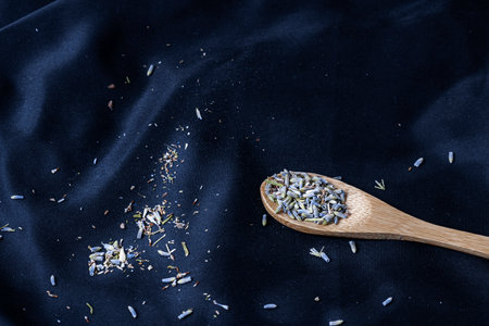 A closeup shot of a wooden spoon with spices on a blue cloth backgroundの写真素材