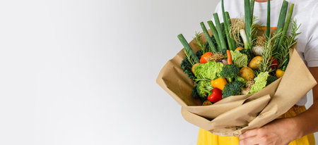 Close-up photo of woman holding fresh vegetables decorated into a bouquet.の写真素材