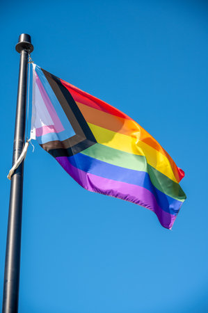 A close up of Rainbow LGBT flag fluttering on blue sky backgroundの写真素材