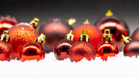 A closeup of red Christmas ball toys on snowの写真素材