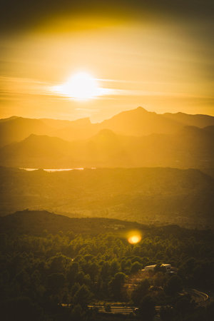 A breathtaking view of the bright, golden sun above mountain silhouettes at sunrise