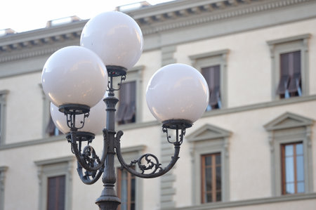A view of black metal round street lamps with four white balls on the background of a buildingの写真素材