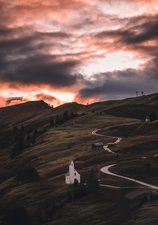 A vertical shot of a curvy walkway on hills leading to the Dolomites during the sunset in South Tyrol, Italyの写真素材