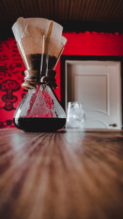 A vertical shot of filtered coffee brewing in a glass on the tableの写真素材
