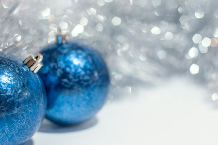 A closeup of blue Christmas ornaments on a white surface with a blurry backgroundの写真素材